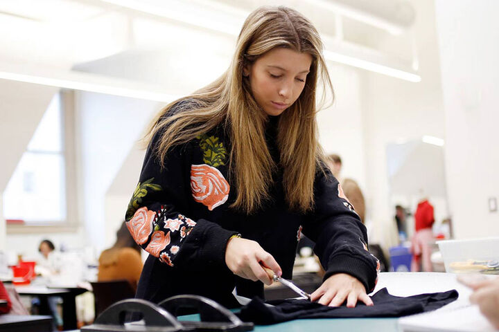 A student works with a piece of fabric on a table.